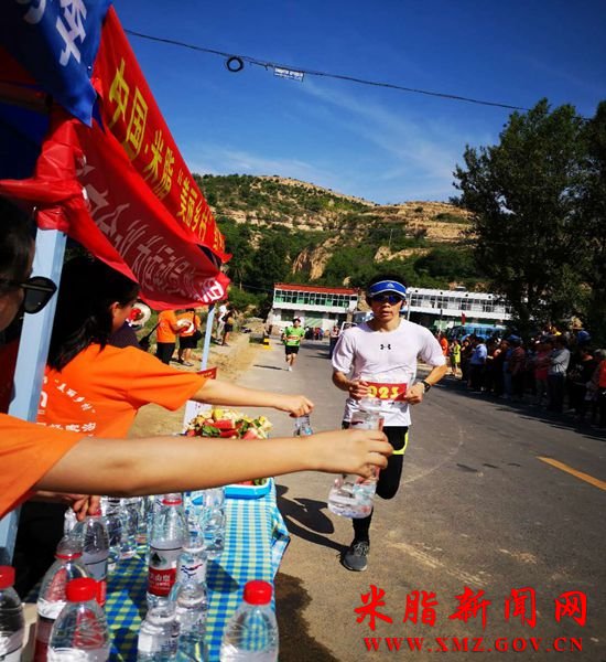 图为补给站的志愿者正在为选手递水